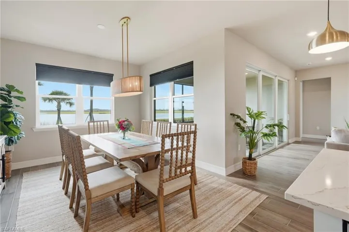 Dining area featuring a contemporary drum pendant light, wood-finish flooring, and large windows with roller shades