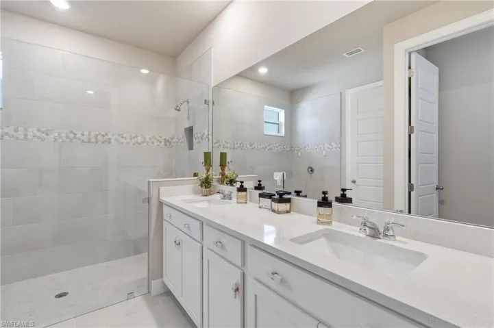 Double vanity with white cabinetry and integrated sinks set into a light-toned countertop
