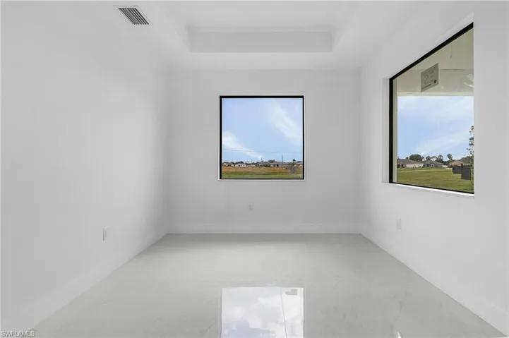 Spare room featuring a tray ceiling and a healthy amount of sunlight