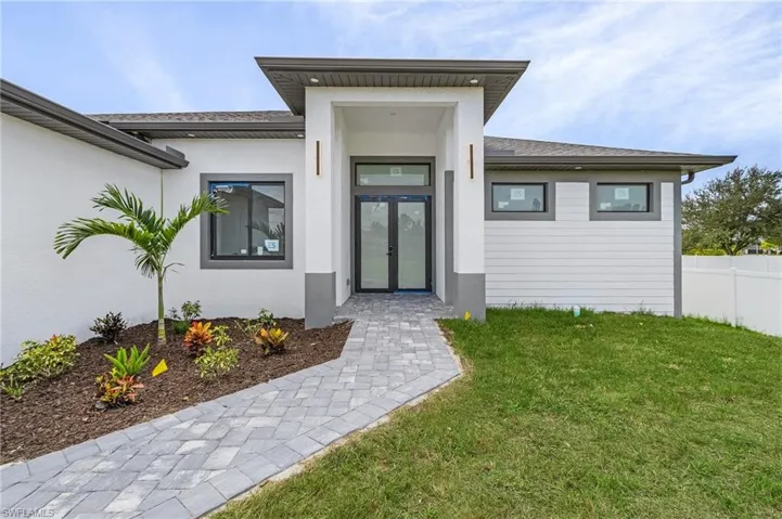 View of exterior entry with a lawn and french doors
