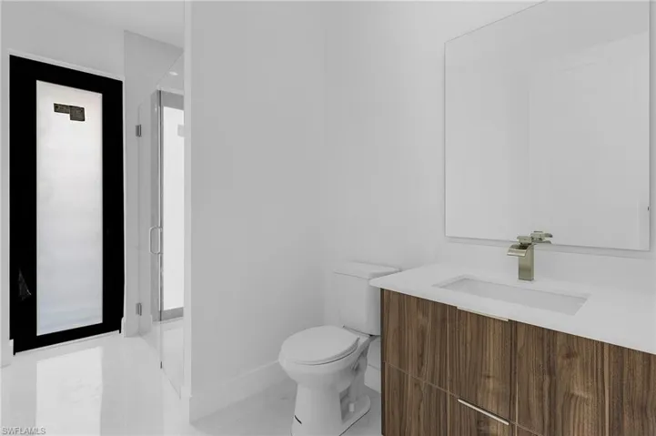 Bathroom featuring tile patterned floors, a shower with door, vanity, and toilet