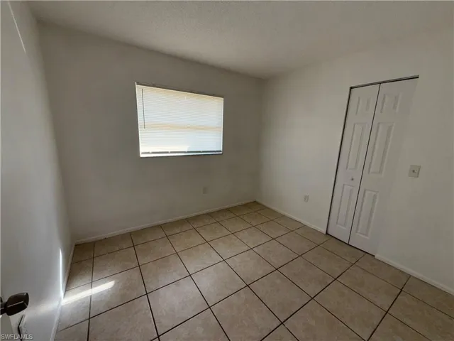 Unfurnished bedroom featuring light tile patterned flooring, a closet, and a textured ceiling