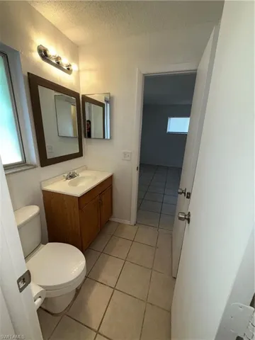 Bathroom with vanity, light tile patterned flooring, and a textured ceiling