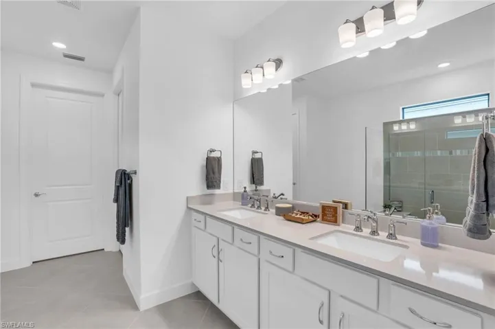 Bathroom featuring dual vanity, walk in shower, and tile patterned flooring