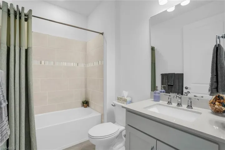 Full bathroom featuring vanity, shower / bathtub combination with curtain, tile patterned flooring, and toilet