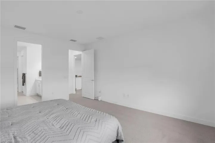 Bedroom with ensuite bath and light carpet