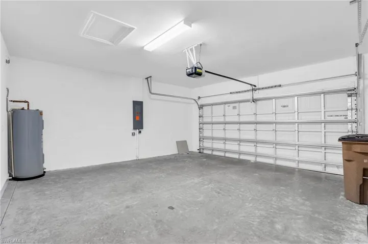 Garage featuring electric water heater, a garage door opener, and electric panel