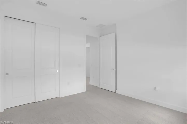 Unfurnished bedroom with light carpet and a closet