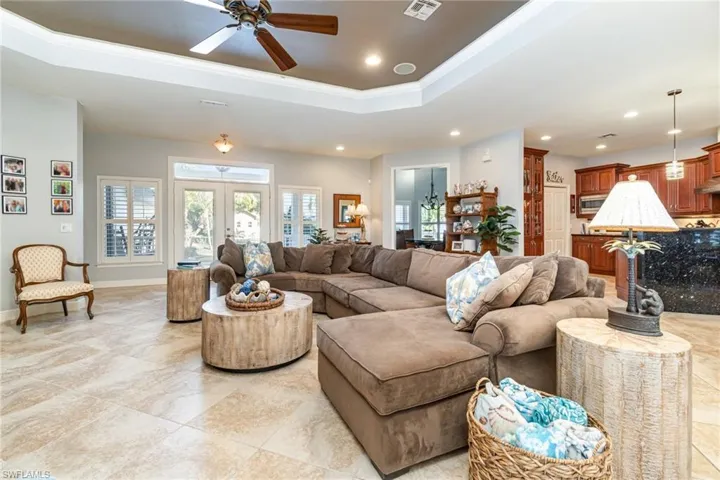 Living area with a tray ceiling, a ceiling fan, recessed lighting, and ornamental molding