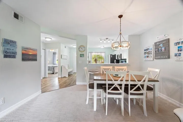Carpeted dining area featuring baseboards and a chandelier