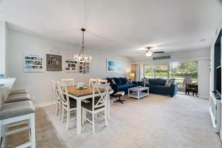 Dining space with light colored carpet, ceiling fan, and a chandelier