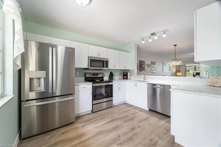 Kitchen with appliances with stainless steel finishes, tasteful backsplash, light countertops, and light wood finished floors