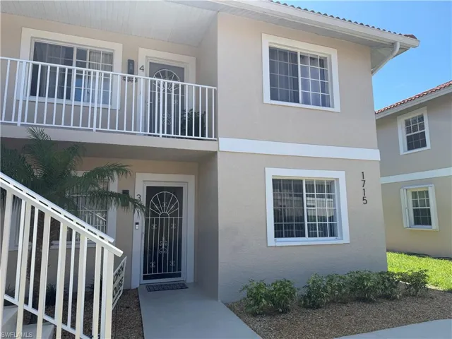 Multi-unit stucco exterior featuring white window frames and a second-story balcony with white railings