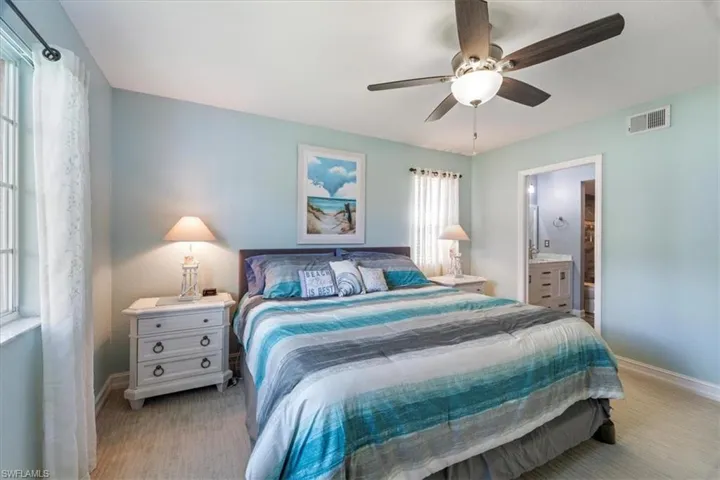 Bedroom with a ceiling fan, ensuite bath, and light carpet