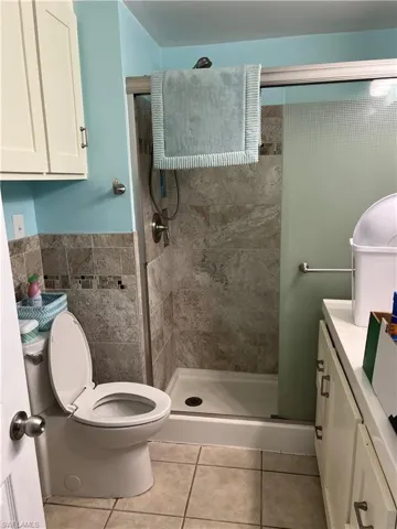 Bathroom featuring vanity, a shower with shower door, toilet, and tile patterned floors