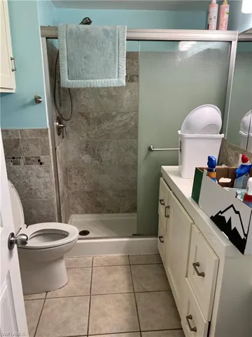 Bathroom featuring vanity, toilet, tile patterned flooring, and an enclosed shower