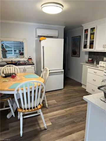 Dining room with an AC wall unit, ornamental molding, and dark hardwood / wood-style flooring