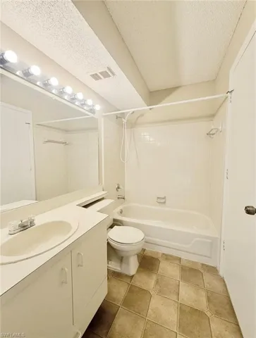 Full bath featuring vanity, toilet, a textured ceiling, and shower / washtub combination