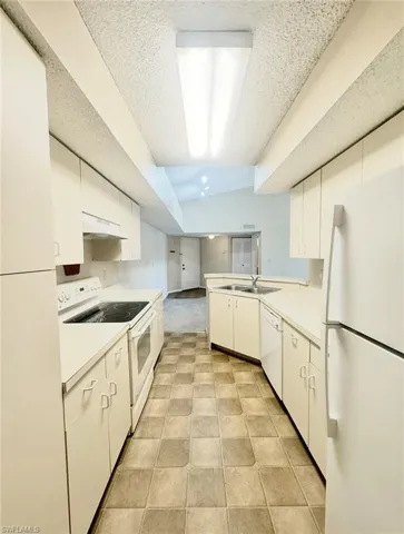 Kitchen with white cabinets, a sink, white appliances, light countertops