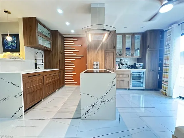 Kitchen featuring beverage cooler, glass insert cabinets, recessed lighting, decorative light fixtures, and light countertops
