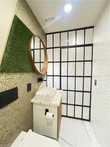 Bathroom featuring tile walls, tile patterned flooring, and vanity