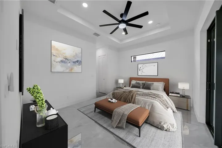 Bedroom featuring a tray ceiling, recessed lighting, a ceiling fan, and light marble finish flooring
