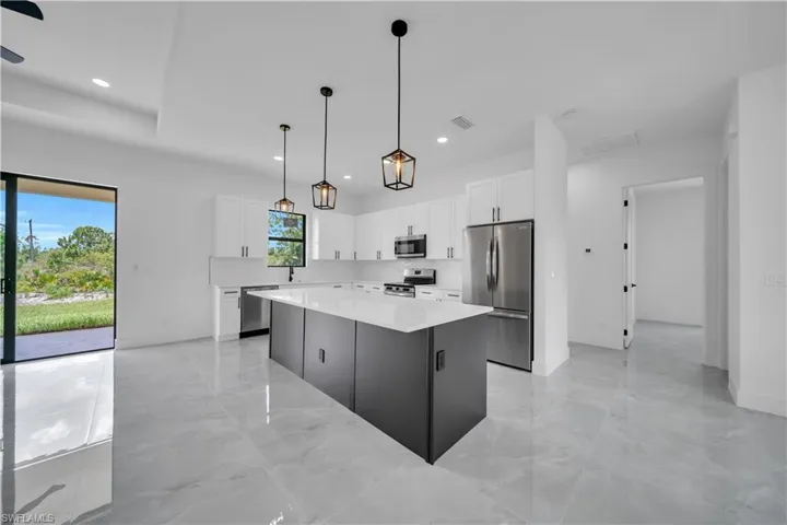 Kitchen featuring stainless steel appliances, light marble finish floors, a center island, white cabinets, and recessed lighting