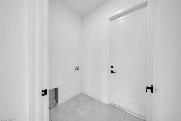 Laundry area featuring washer hookup and light marble finish floors