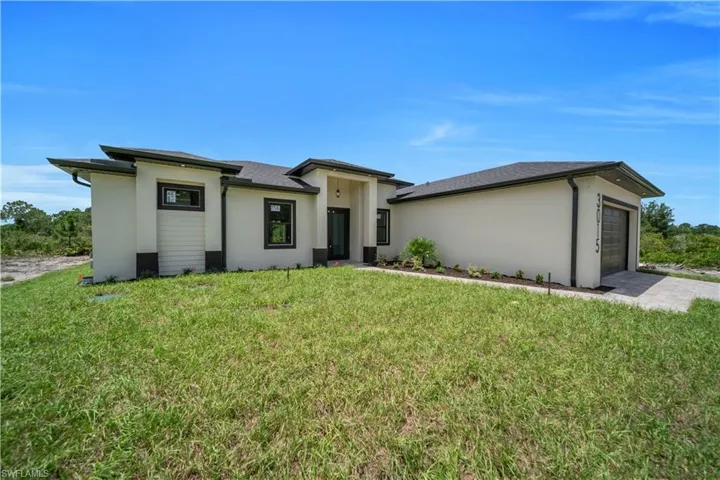 Prairie-style house featuring an attached garage, stucco siding, and a front lawn