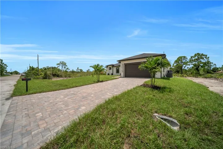 View of front of home featuring a front yard, driveway, a garage, and stucco siding