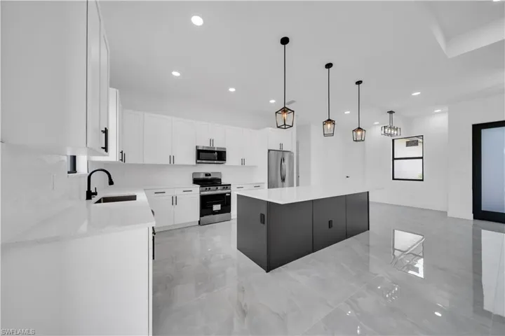 Kitchen with stainless steel appliances, light marble finish floors, a center island, recessed lighting, and white cabinetry