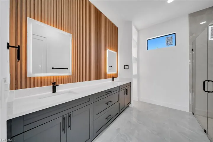 Bathroom featuring double vanity, a stall shower, and marble finish floors