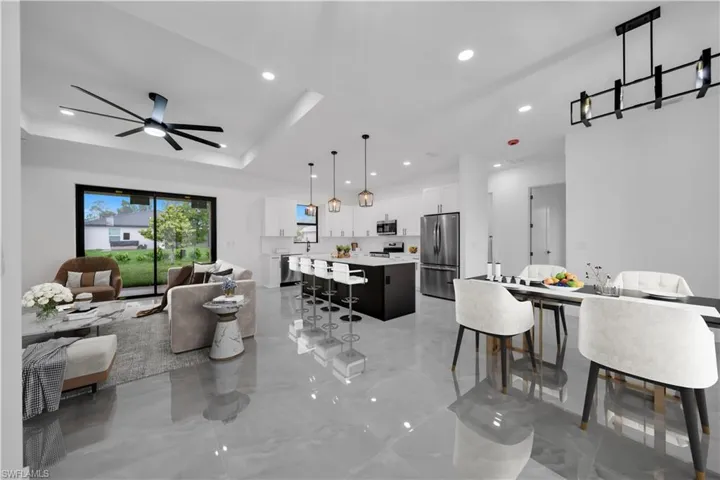 Living area featuring recessed lighting, a ceiling fan, light marble finish flooring, and a tray ceiling