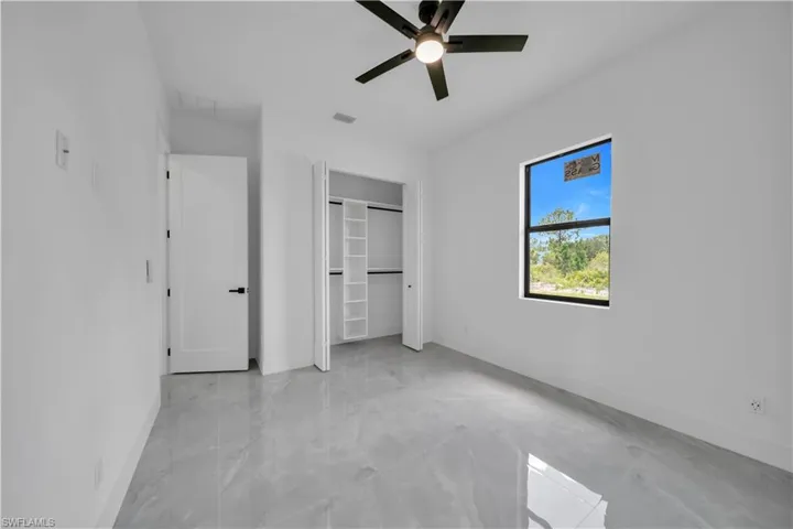 Unfurnished bedroom with light marble finish flooring, a ceiling fan, and a closet
