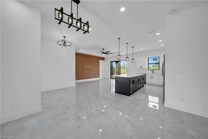 Kitchen with ceiling fan, a chandelier, light countertops, open floor plan, and a kitchen island