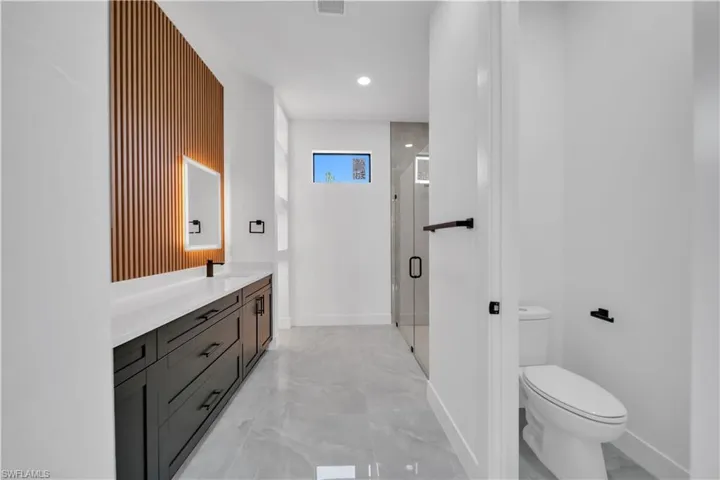 Full bath with marble look tile flooring, vanity, a shower stall, and recessed lighting