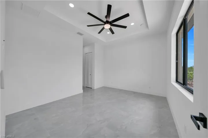 Spare room featuring marble look tile flooring, a raised ceiling, recessed lighting, and ceiling fan
