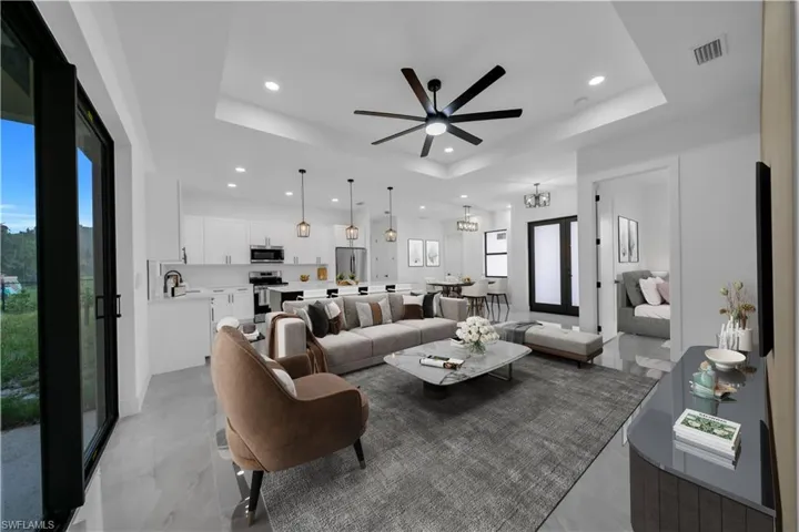 Living room with a raised ceiling, recessed lighting, and ceiling fan