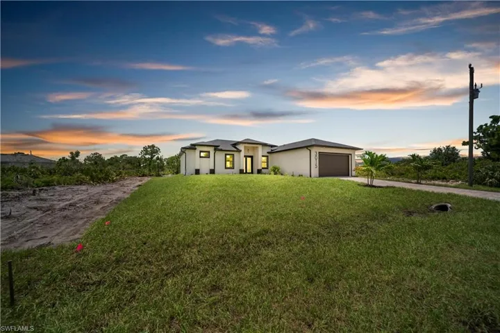 View of front of property with driveway, an attached garage, a lawn, and stucco siding