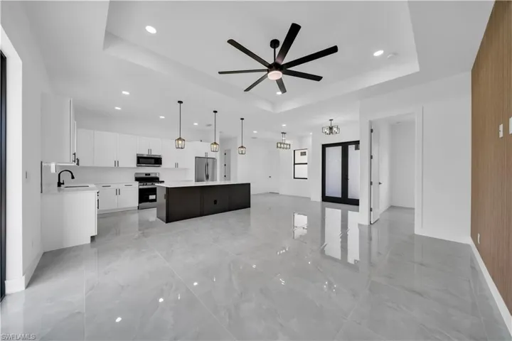 Kitchen featuring stainless steel appliances, a raised ceiling, light marble finish floors, recessed lighting, and ceiling fan