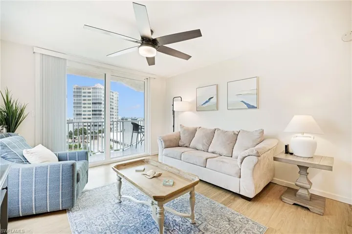 Living room with a ceiling fan, light wood finished floors, and a view of city