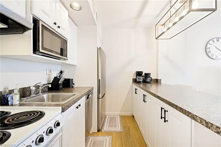 Kitchen featuring extractor fan, appliances with stainless steel finishes, light wood-type flooring, and white cabinets