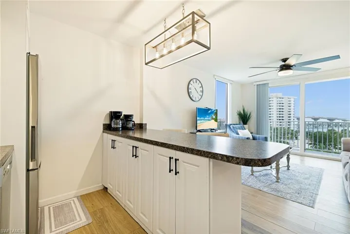 Kitchen with a peninsula, open floor plan, a ceiling fan, and dark countertops