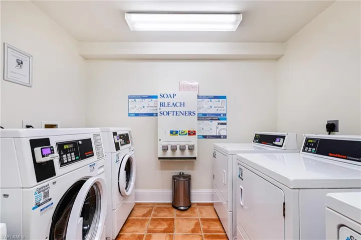 Shared laundry room with independent washer and dryer and light tile patterned floors