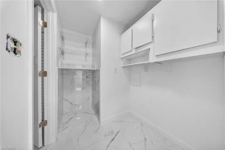 Utility space featuring white cabinetry, built-in shelving, and a patterned tile floor