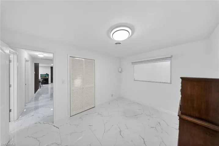Bright room featuring white walls and white marble-look flooring