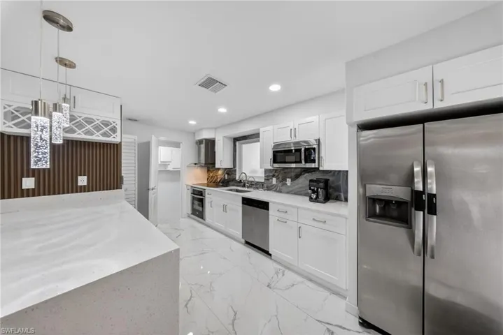 Contemporary kitchen featuring white cabinetry, stainless steel appliances, and white stone countertops