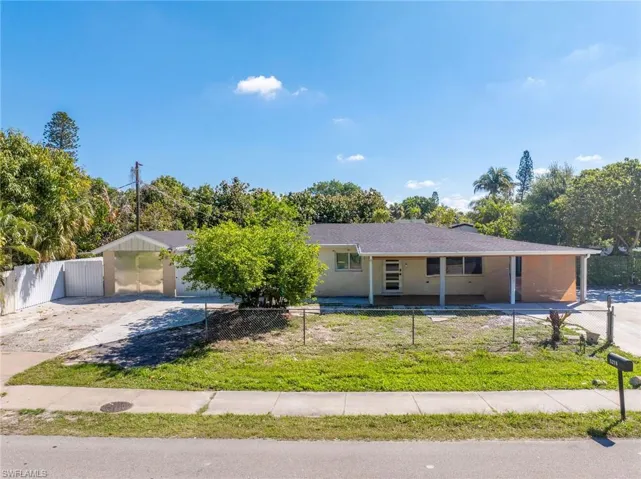 Single-story residence featuring a carport, covered porch, and a fenced front yard