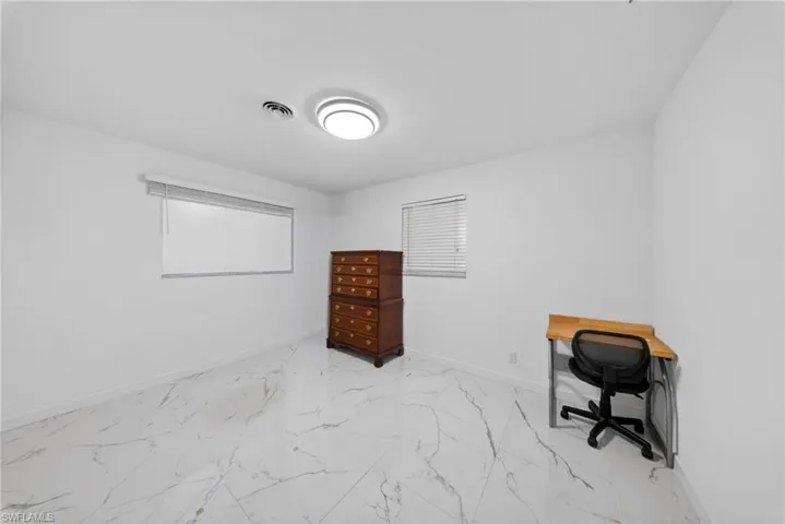 Room featuring white walls, marble-finish tile flooring, a contemporary flush mount ceiling light, and two windows with blinds