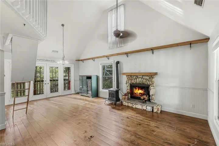 Unfurnished living room with high vaulted ceiling, wood-type flooring, ceiling fan, and french doors
